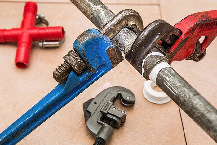 Professional plumber in uniform repairing a kitchen sink pipe